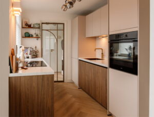 Moderne parallel keuken in Japandi stijl met notenhouten en beige frontjes, BORA kookplaat en wijnklimaatkast - gezellige binnenkijker keuken van trotse I-KOOK klant uit Tilburg