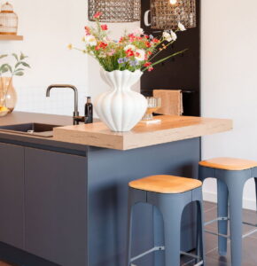 Grijze moderne keuken met verhoogd eiken houten barblad en 2 barkrukken met houten zitting Grijze moderne keuken met verhoogd eiken houten barblad en 2 barkrukken met houten zitting