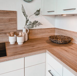 Moderne witte keuken met houten aanrechtblad, kookplaat achterwand en smetplint
