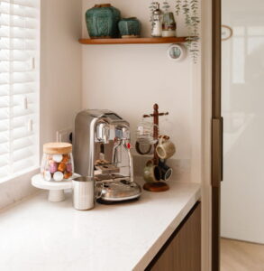 Marmerlook keukenblad composiet wit met verfijnde grijze aders in een moderne houten keuken met barista koffiemachine - Binnenkijker uit Tilburg bij trotse klanten van I-KOOK