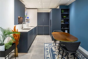 Moderne donker blauwe keuken met open vakkenkast, verborgen bijkeuken + vintage-look eettafel en stoelen