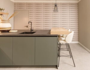 KEUKENTRENDS 2026 - Greeploze groene keuken met eikenhout ontbijtbar en 2 comfortabele barkrukken - donkergrijs natuursteenlook Greengridz keukenblad en Gun Metal zwarte kraan en spoelbak