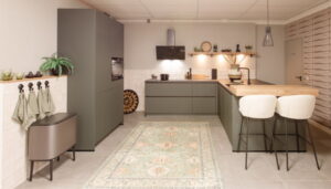 Vintage moderne keuken groen met eiland, houten bar en wandplank, retro afvalbak en seventies-look keukenaccessoires in de keukentrends van 2026 Vintage moderne keuken groen met eiland, houten bar en wandplank, retro afvalbak en seventies-look keukenaccessoires in de keukentrends van 2026