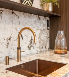 Lichte natuursteen aanrechtblad van keramiek + achterwand, Quooker messing patina en Gold Lanesto spoelbak goud en zeeppomp Lichte natuursteen aanrechtblad van keramiek + achterwand, Quooker messing patina en Gold Lanesto spoelbak goud en zeeppomp