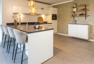 Moderne witte keuken met eiland - wit schiereiland met grijs blad en comfortabele barkrukken Moderne witte keuken met eiland - wit schiereiland met grijs blad en comfortabele barkrukken
